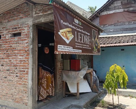 TETAP TRADISIONAL: Mutmainah di pintu dapur produksi ledrenya. Bertahan pakai anglo dan arang. (Foto: Ahmad Wahyu Rizkiawan/Bojonegoro Raya)
